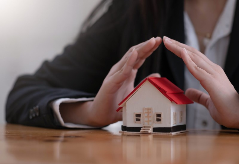 Protect your house concept. Small toy house covered by hands Protect your house concept. Small toy house covered by hands.